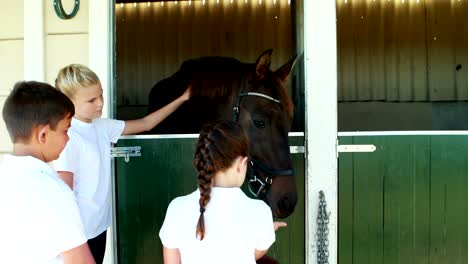 kids stroking horse in stable 4k