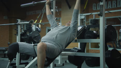 man with prosthetic leg performing bench press exercise in a gym