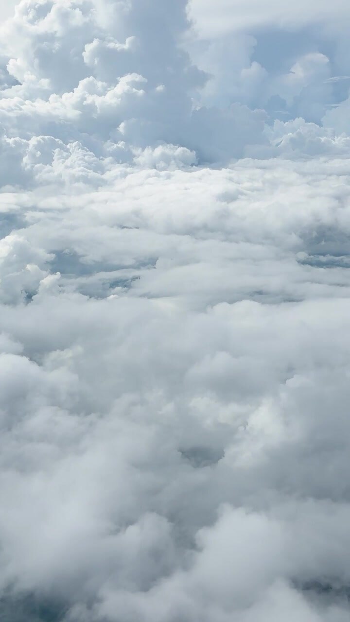 A serene vertical perspective flying over a dense layer of soft white cumulus clouds.