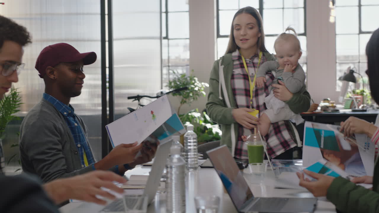 business people meeting team leader woman mother holding baby discussing corporate project with colleagues multitasking in modern office workplace