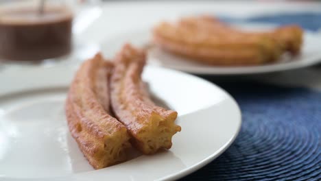 spanish snack fried dough is called churros, next to a hot chocolate sauce to dip them in