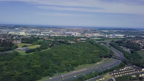 Luftaufnahmen-Einer-Drohne,-Die-über-Wohnhäuser-Mit-Blick-Auf-Eine-Viel-Befahrene-Autobahn-Mit-Fließendem-Verkehr-In-Einem-Vorort-Von-Yellow-Wood-Park-Durban-Fliegt