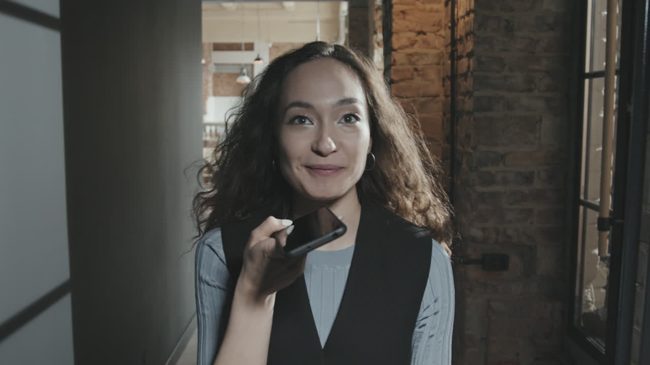 Young Cheerful Businesswoman Recording Voice Message on Smartphone