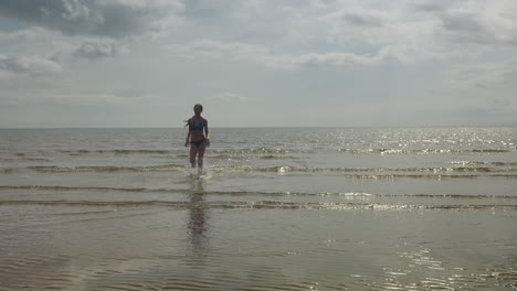 chica joven corriendo, agua del océano, ubicación de la playa, sol dorado, cámara lenta