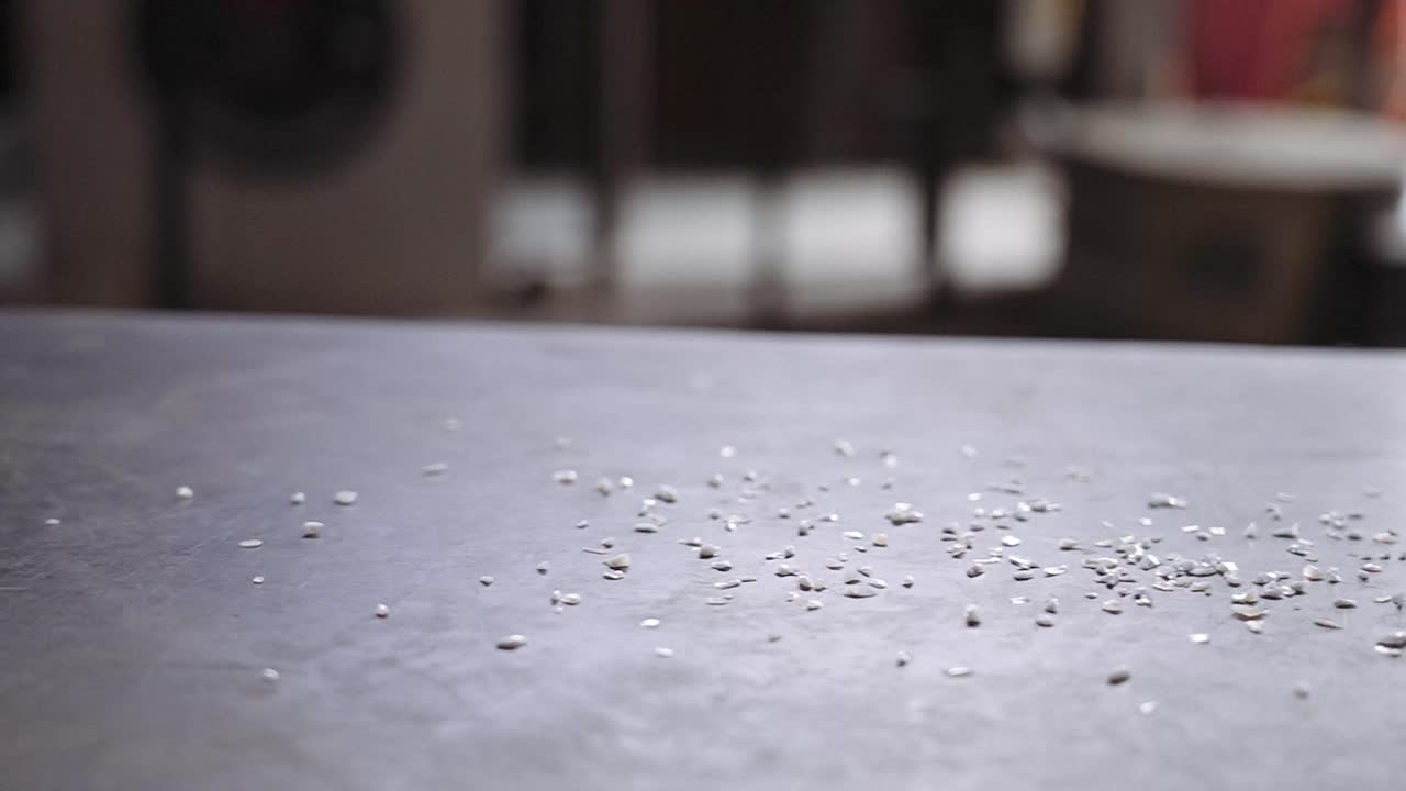 una mano sacando pedazos de vidrio sobre una mesa de metal