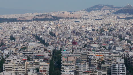 una toma aérea estrecha de los edificios blancos de atenas y la acrópolis en el fondo