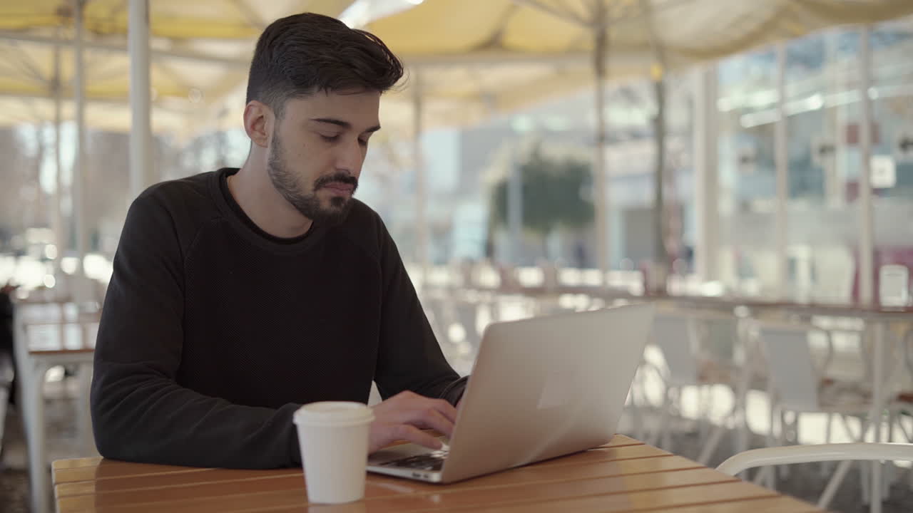 joven enfocado usando una computadora portátil en un café