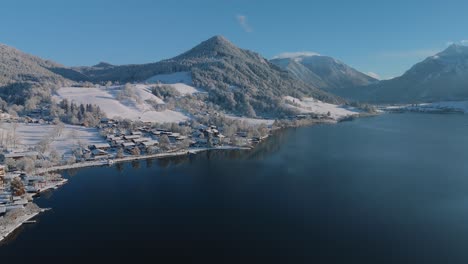 lake schliersee with white snow winter landscape, mountains and dark blue water