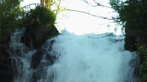 Water-flowing-down-a-stony-cliff-at-Burney-Falls,-lush-forest-waterfall-in-California