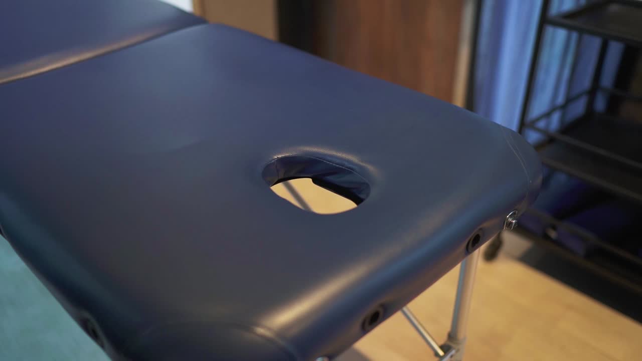 primer plano de una mesa de masaje azul en una habitación de hotel. con un agujero en la cara para la comodidad del cliente durante los tratamientos. sugiriendo una experiencia relajante y profesional como un spa dentro del entorno de hospitalidad