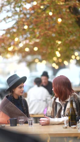 two women talking outdoors in autumn cafe