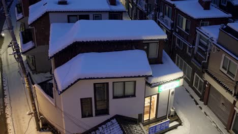 Snow blanketing rooftops of houses and small businesses creates a serene winter atmosphere in a quiet residential neighborhood as dusk settles, inviting a sense of tranquility