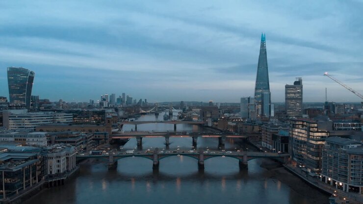 Dolly forward drone shot over the Thames London towards the shard and Canary Wharf at blue hour
