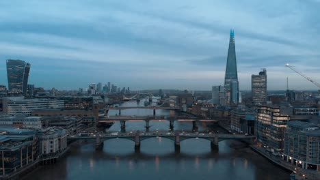 dolly forward drone shot over the thames london towards the shard and canary wharf at blue hour