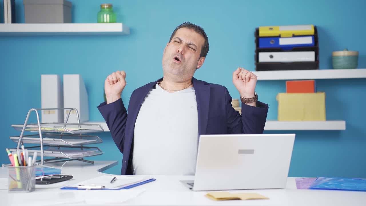 Sleepy businessman yawns looking at camera.