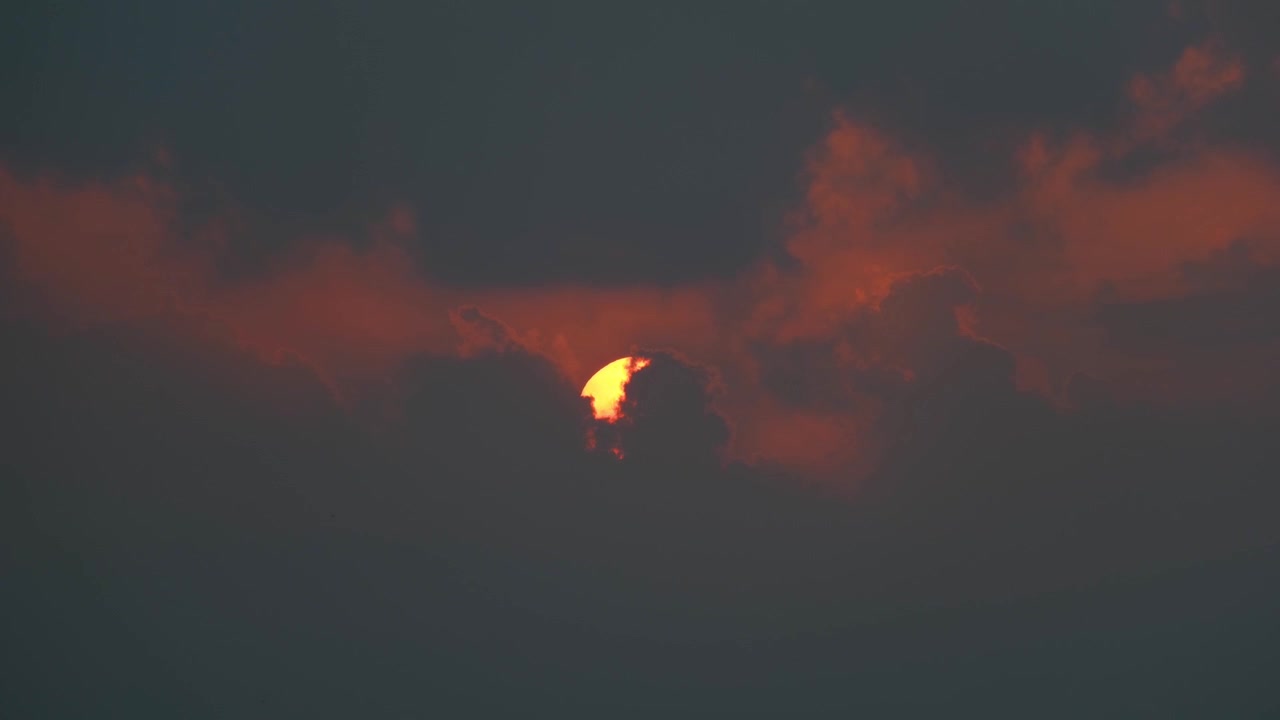 Sun rises through dark clouds at morning