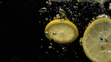 super slow motion shot of falling lemon into water.