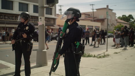 2 police officers armed with a shotgun during a protest in front of the city hall