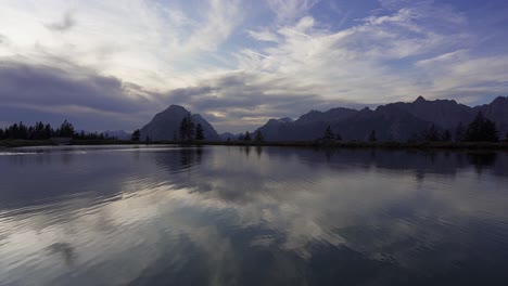 slow panning shot of a perfect lake in the alps with mountain reflections, kaltwassersee, near seefeld in tirol in austria