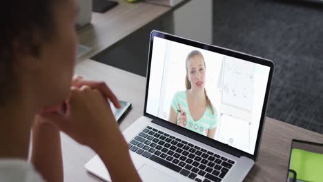 African-american-businesswoman-sitting-at-desk-using-laptop-having-video-call-with-female-colleague