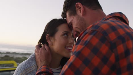 pareja caucásica romántica sentada en un buggy de playa abrazándose y tocando las cabezas