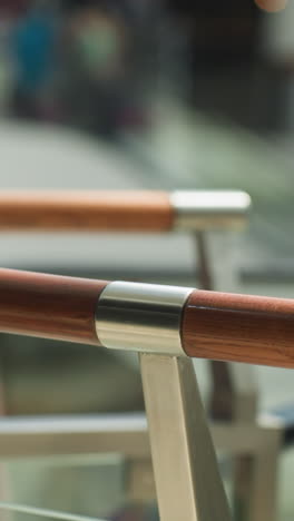 un fondo borroso de un centro comercial ocupado, capturado desde una perspectiva en primera persona con una cámara portátil, centrándose en las elegantes barandillas de madera
