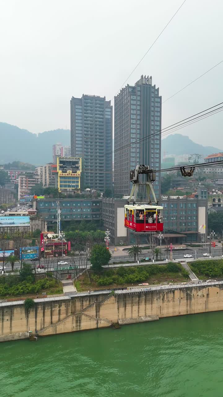 Vertical establishing drone shot of Chongqing cityscape with cable car above Yangtze River during the day in Yuzhong District, China