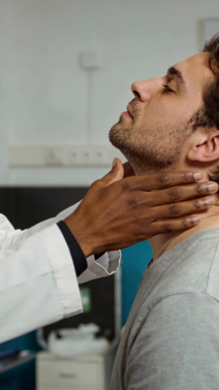 Vertical video: Tilting man back, doctor palpating neck for exam in clinic, white coat, copy space