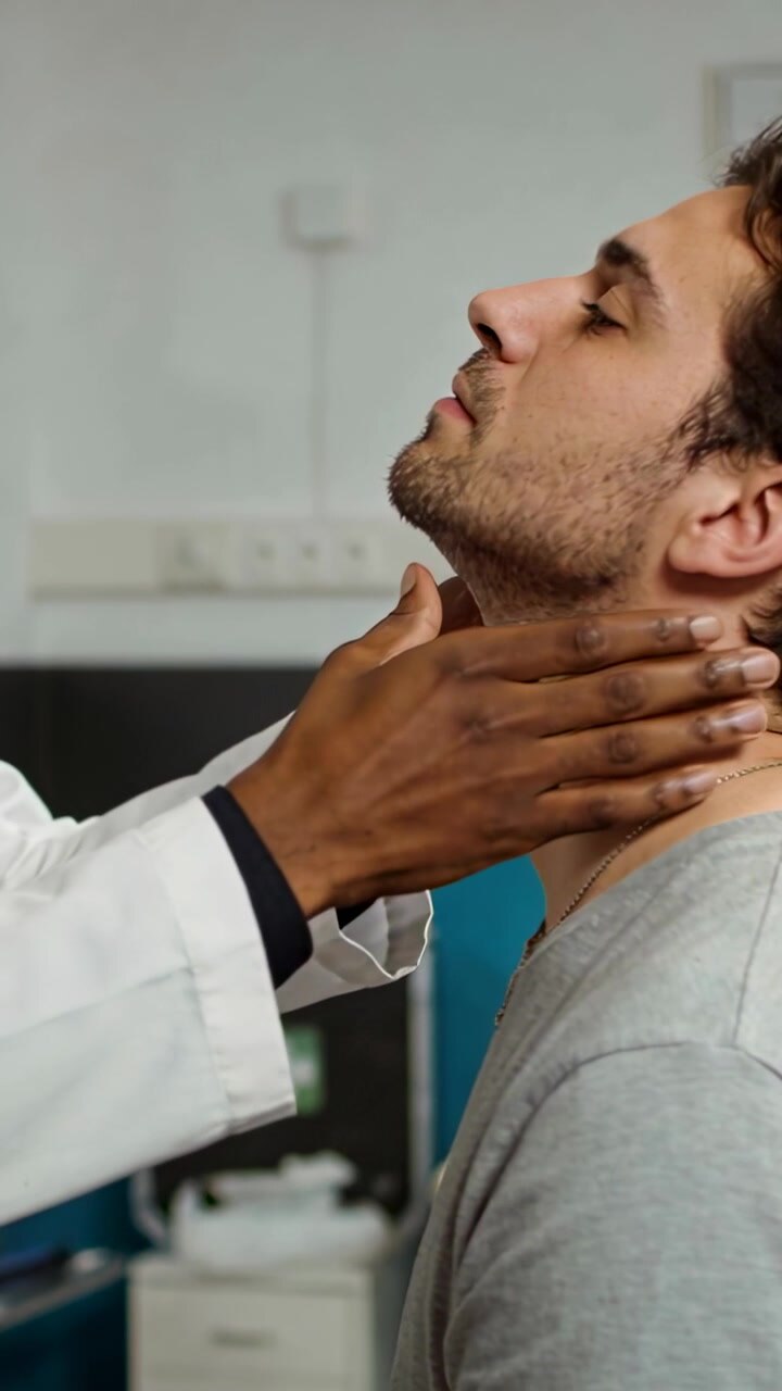 Video verticale: Uomo che inclina la testa all'indietro, medico che palpa il collo per un esame in clinica, camice bianco, spazio per il testo.