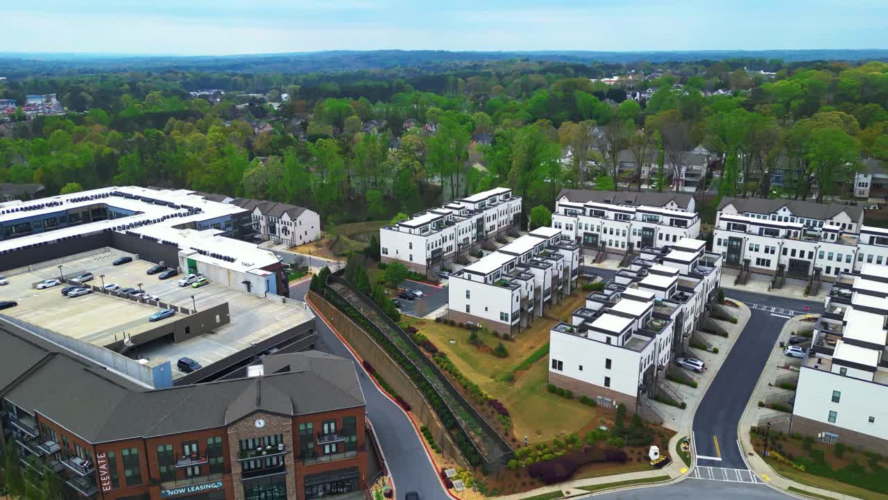 Parking cars on roof of Building near modern housing area with townhouses. Aerial forward wide shot. Green trees in suburbia. Georgia, USA.