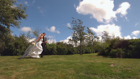 happy newlywed couple running in a park