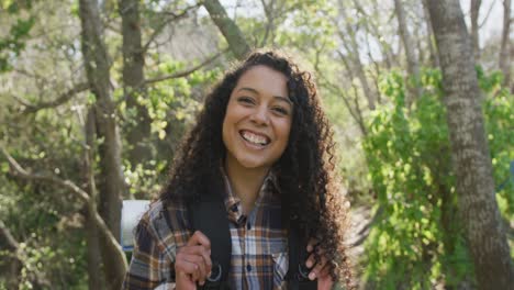 portrait of smiling biracial woman in forest during hiking in countryside