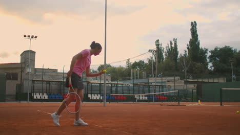 Slow-motion:-Young-Caucasian-teenager-female-tennis-player-serving-during-a-game-or-practice.-Tennis-Player-Serving-On-The-Clay-Court.