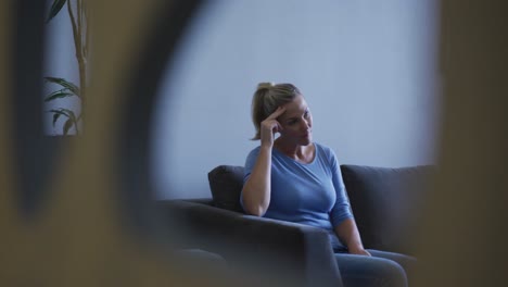 mujer caucásica cansada sentada en el sofá en la sala de espera del hospital