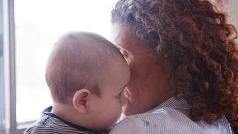 baby grandson looking over grandmothers shoulder as she cuddles him