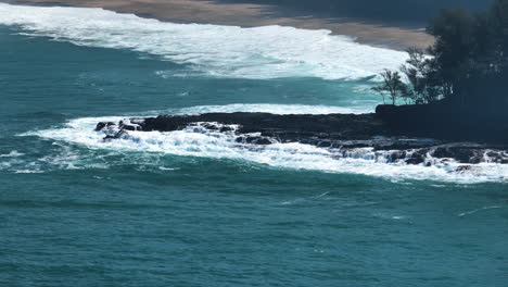 aerial telezoom of large waves crashing the coastline of kauai, in sunny hawaii