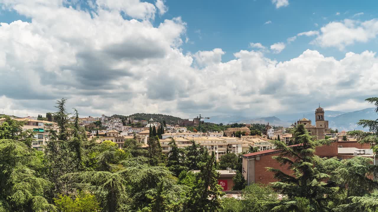 Dramatic cloudscape drifting above granada's historic andalusian cityscape, capturing architectural beauty under bright summer sky