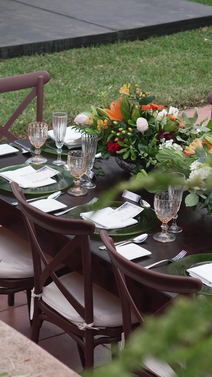 Bryllupsfestbord med farverige blomsteropsatser. Bordet er dækket med elegant og sofistikeret glasstel