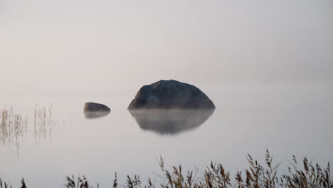 Friedliche,-Ruhige-Atmosphäre,-Seewasser-Mit-Steinen-In-Der-Mitte,-Dunstiger-Nebel,-Der-Sich-Bewegt