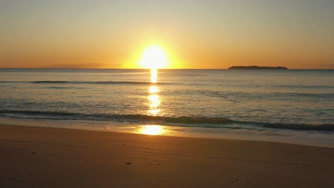 Beach-sunrise-shining-golden-foamy-waves-rolling-towards-sand-beach-sunlight-static-shot