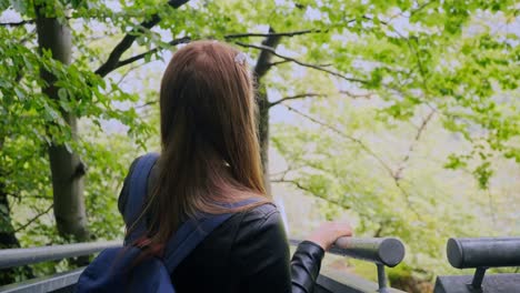 Young-brunette-woman-looks-into-the-forest-ahead-and-points-in-forward-direction