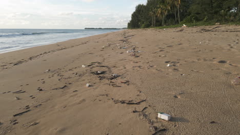 a beautiful sandy beach that is littered with washed up plastic and other rubbish