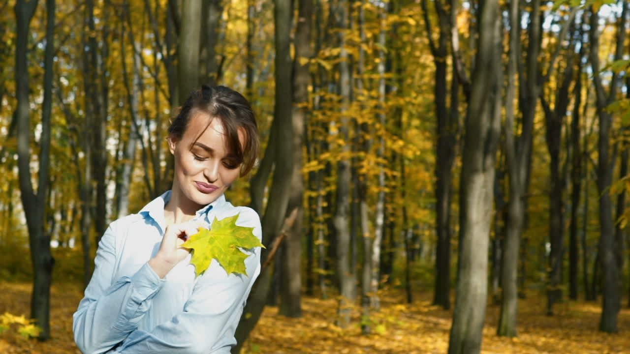 Sunny autumn day in park. Young woman spending time in autumn park