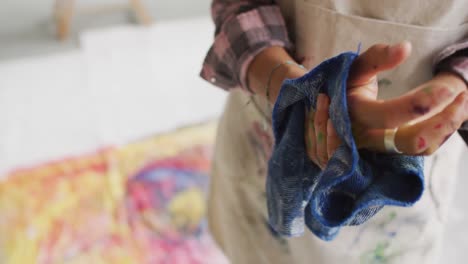 video of biracial female artist cleaning hands with cloth