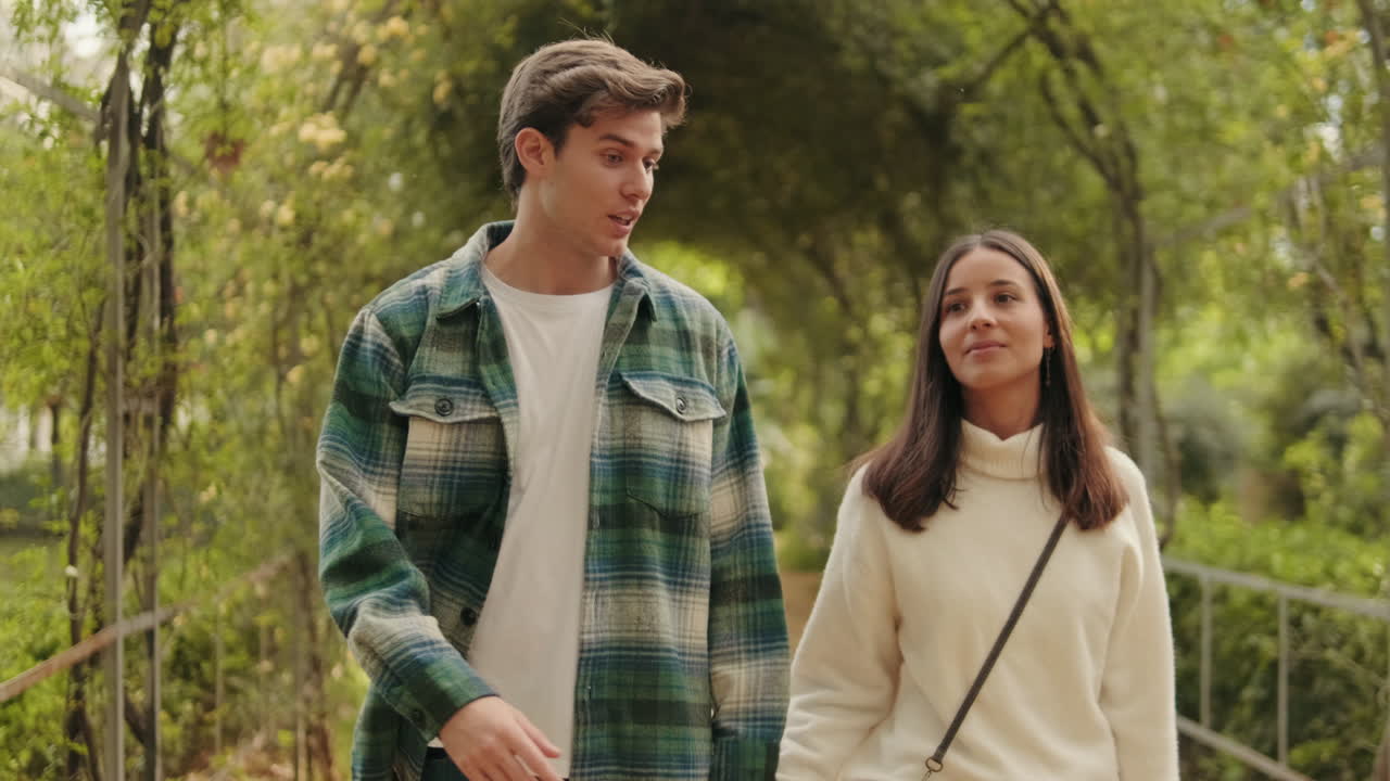 Happy young partners man and woman walking inside green arch