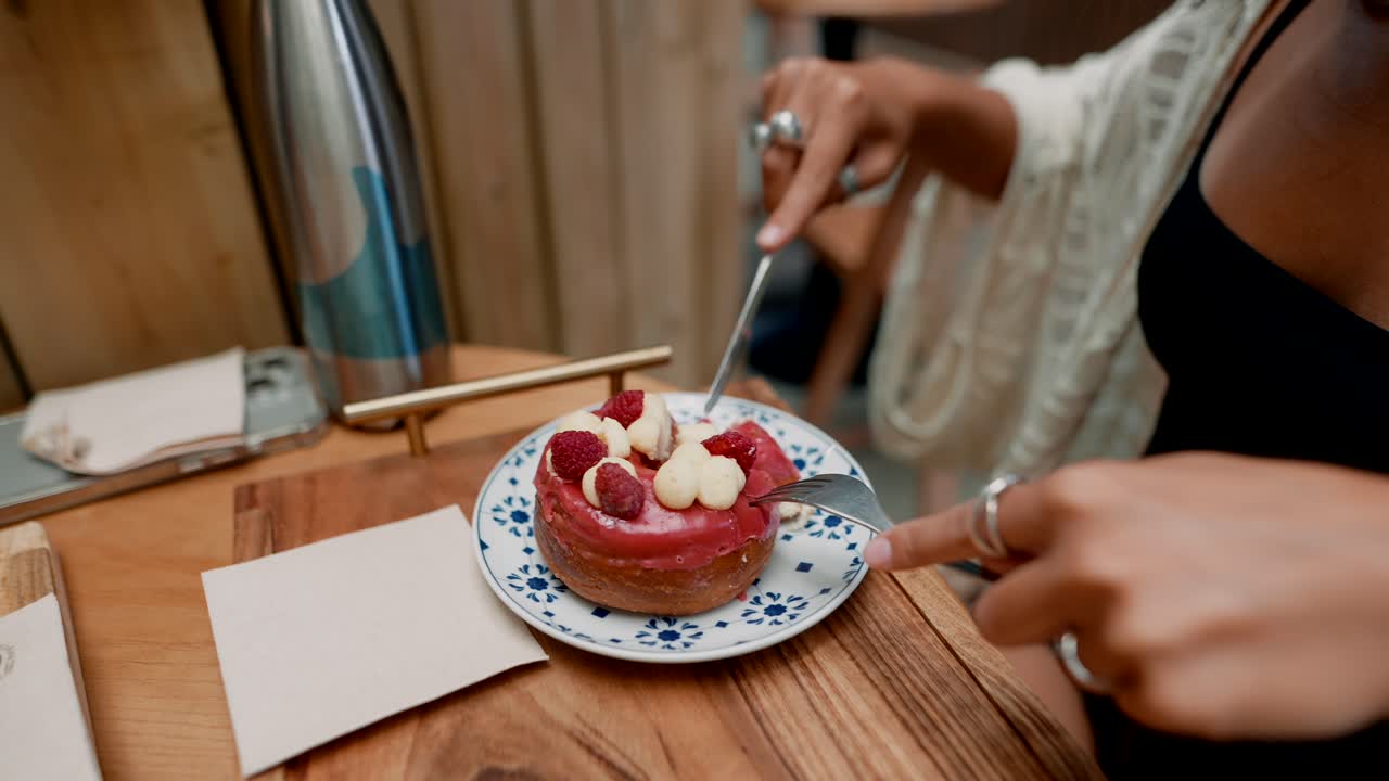 A woman eating a raspberry donut