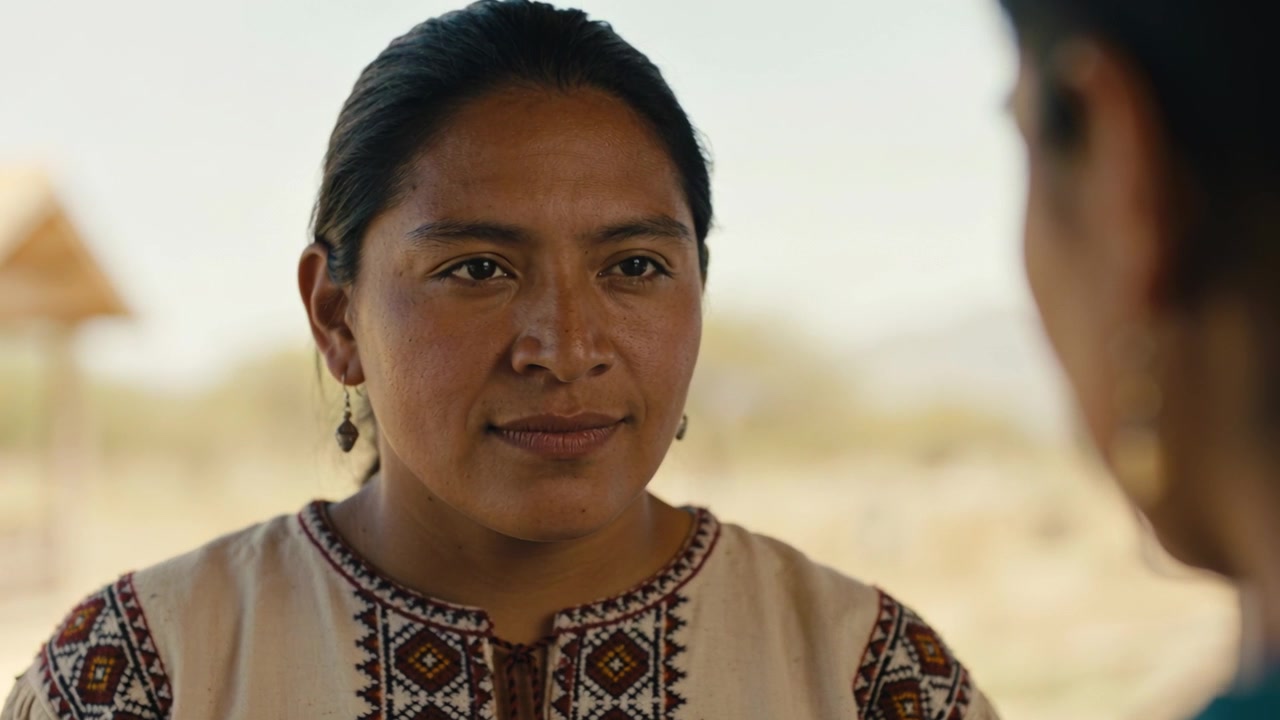 Listening Indigenous woman responding to offscreen question during rural talk in embroidered blouse