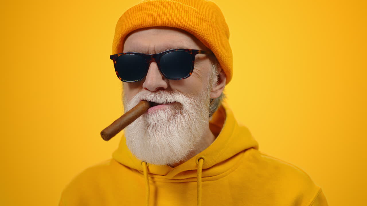 un anciano relajándose en el interior, un anciano satisfecho fumando en un estudio moderno.