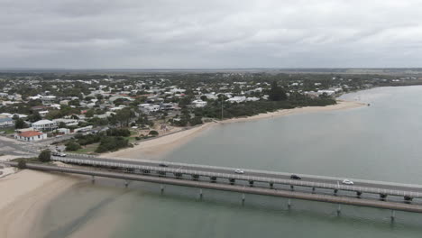 AERIAL-PAN-RIGHT-Vehicles-Crossing-River-Bridge-At-Costal-Town