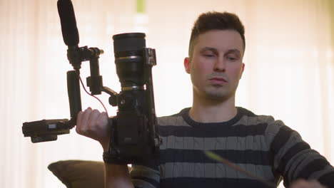 tv technician fine tuning camera equipment using a screwdriver. person adjusts camera rig, checking lens, microphone, and setup in studio environment with green wall and lighting